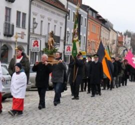 Prozession über den Stadtplatz. Angeführt von Ministranten wird die Statue des Hl. Sebastian vor den Vereinsabordnungen getragen.